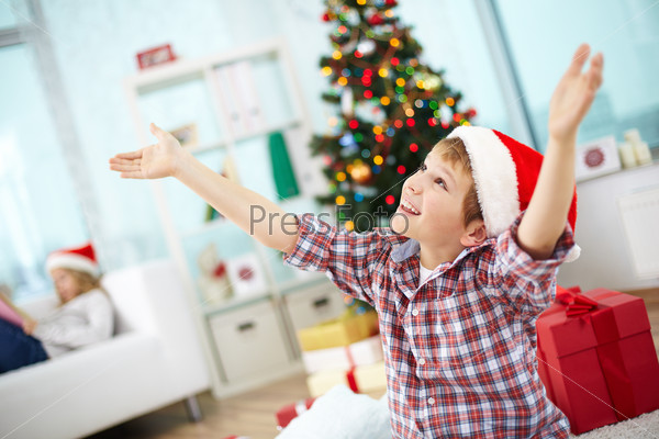 Portrait of joyyful boy with raised arms looking upwards on Christmas evening