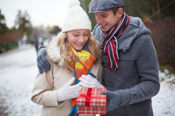 Image of affectionate guy giving his girlfriend Christmas present outside