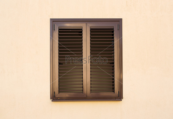 Detail of a window with shutters closed on yellow wall