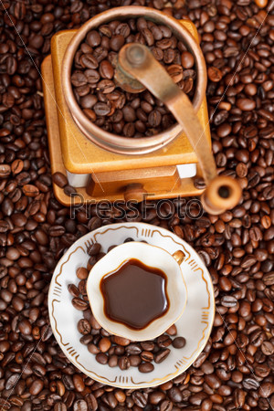 Top view small cup of coffee and roasted coffee beans with retro copper manual mill, stock photo