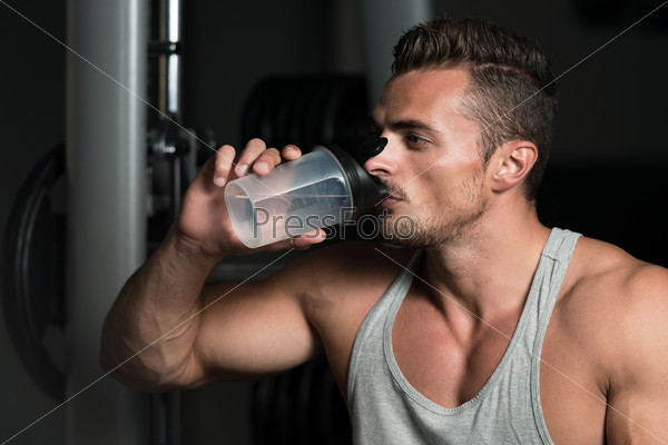 Fit Man Drinking Water. Healthy Young Man Resting And Drinking Water At Gym