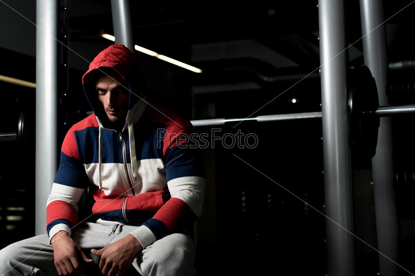 Attractive Young Man Sitting On Bench. Portrait Of A Young Muscular Sporty Fit Caucasian Man Resting At The Bench