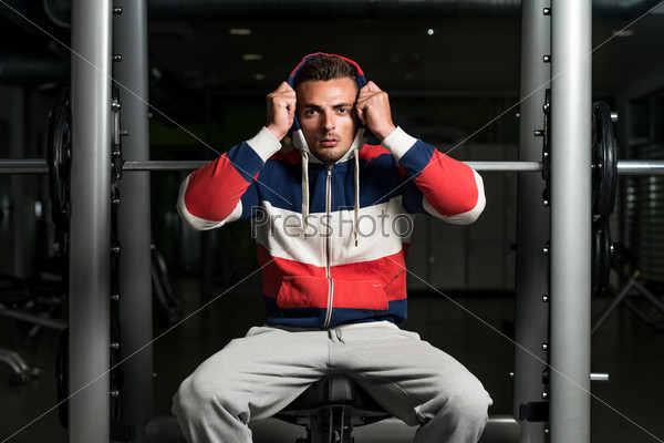 Attractive Young Man Sitting On Bench. Portrait Of A Young Muscular Sporty Fit Caucasian Man Resting At The Bench