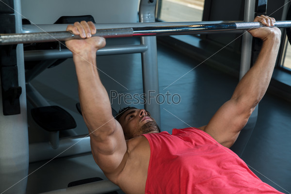 Weightlifter On Bench press. Young Men In Gym Exercising On The BenchPress