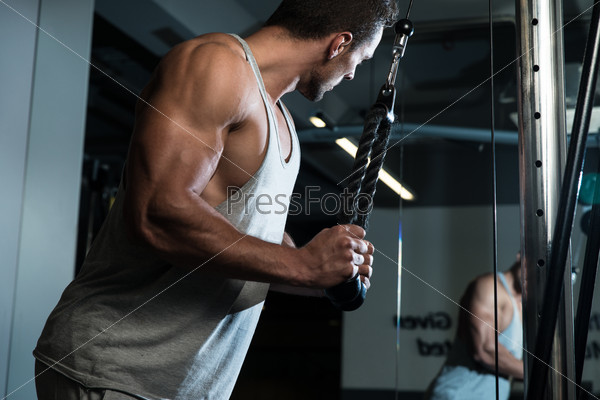 Triceps Exercise. Fit Man On The Triceps Pull down Weight Machine At A Health Club
