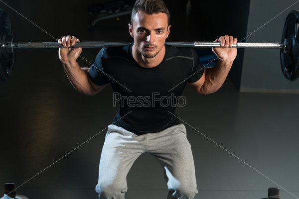 Young Man Exercising With Barbell Squats