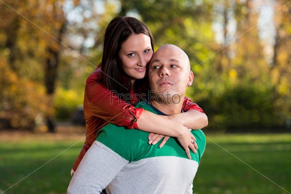 Man Carrying Woman Piggyback At Autumn Woods