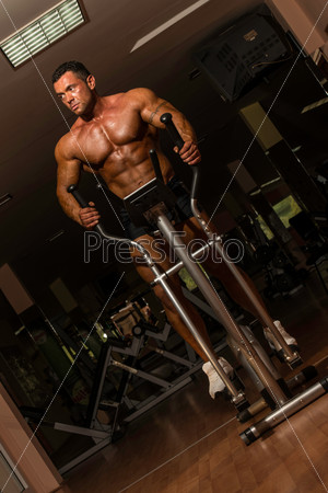 shirtless bodybuilder using the elliptical machine