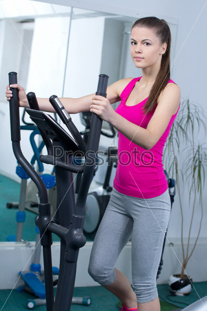 Fitness Woman. Happy woman training at the gym on cross trainer