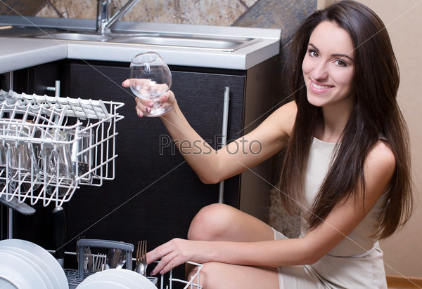 Kitchen Woman. Girl in the kitchen using dishwasher. view of young woman in kitchen doing housework