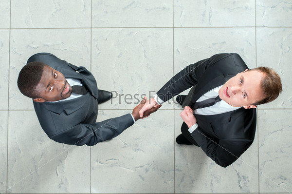 African businessman shaking hands with a caucasian one. view from above