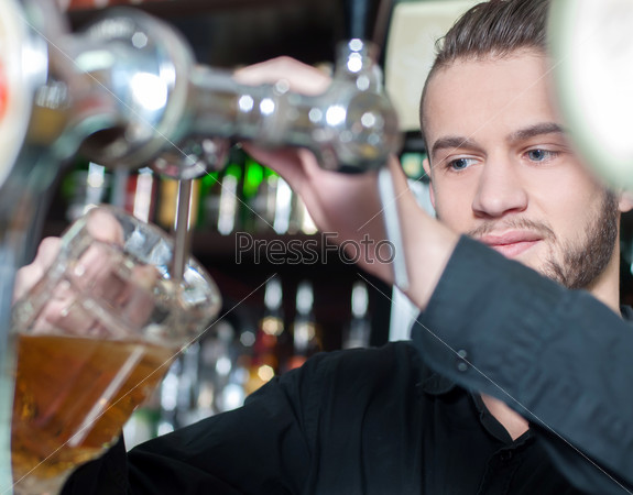 Man hand pouring of beer behind the bar