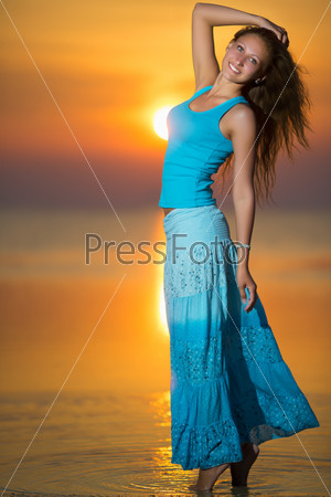 Smiling blonde in blue t-shirt and skirt posing at the sunset