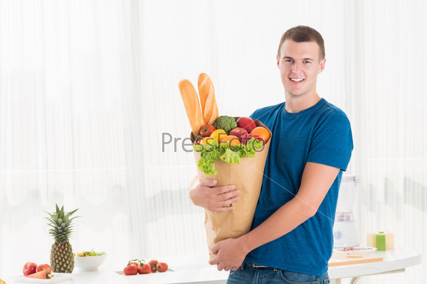 Portrait of a modern guy holding a paper bag with groceries