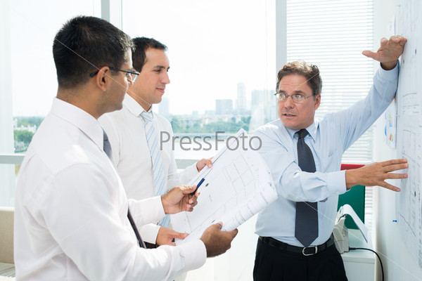Confident businessman explaining sketch to his colleagues at meeting