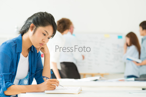 Teenage girl sitting in classroom at a textbook