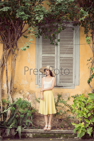 Copy-spaced image of an attractive young woman standing near the old house outside