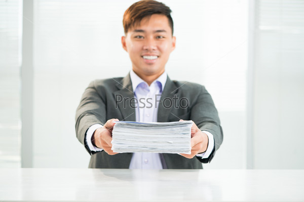 Portrait of a young businessman holding a heap of documents before deadline