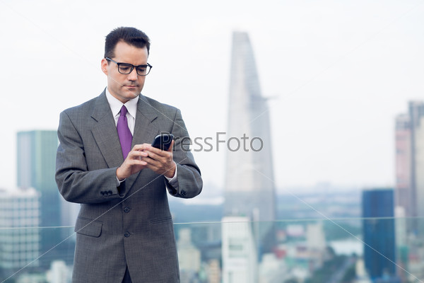 Copy-spaced image of a businessman making a serious call by smartphone standing on the roof