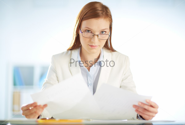 Young businesswoman sitting in office and working with papers