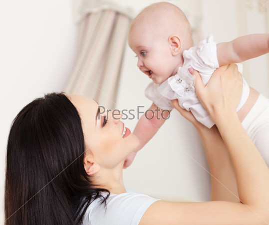 Happy smiling mother with six month old baby girl indoor