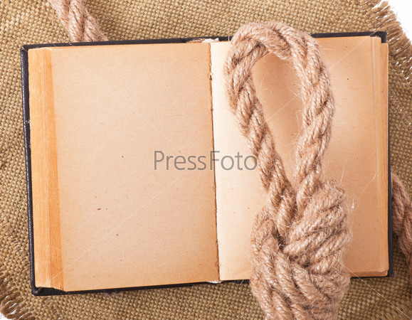Knot sea and old book on background of the old fabric