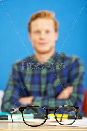 Pair of horn rimmed glasses on a graphic designer\'s desk. Shallow Depth of Field, focus on the glasses.