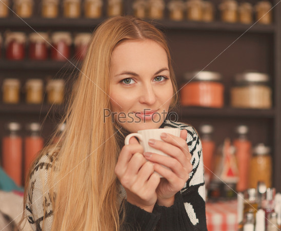 Smiling blond woman drinking coffee in cafe