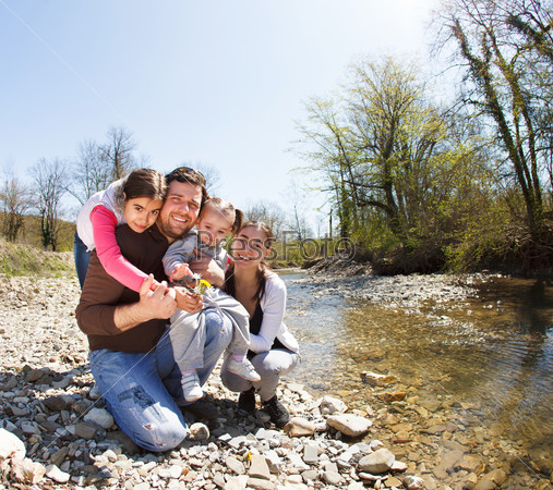 Happy young family with two little daughters near the mountain river outdoors