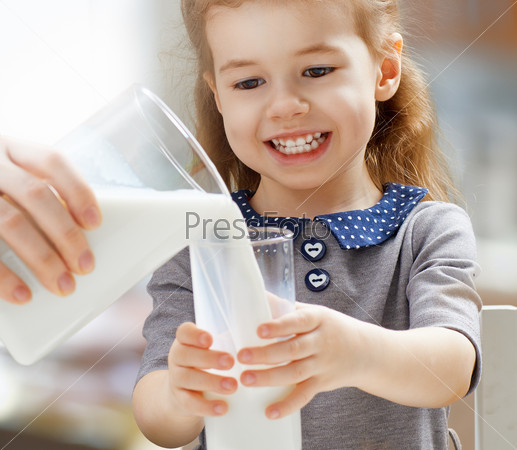 Girl drinking milk at the kitchen, stock photo