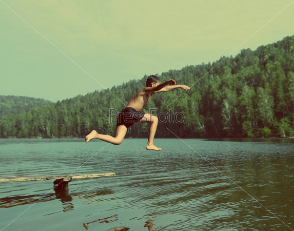 boy jumping in lake at summer vacations – vintage retro style