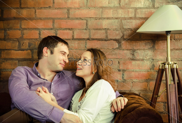 Happy couple talking and sitting on sofa