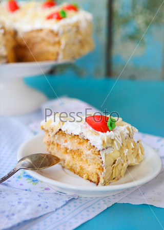 Piece of carrot cake with icing and little carrot on blue wooden background