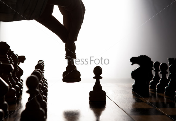 silhouette hand of man making a move chess figure