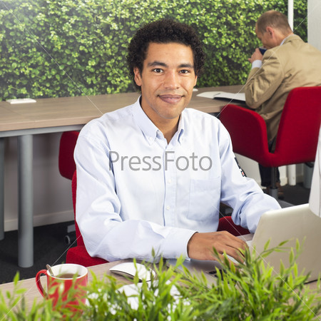 Man, working behind a laptop in a shared office space
