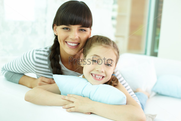 Portrait of happy girl and her mother looking at camera with smiles