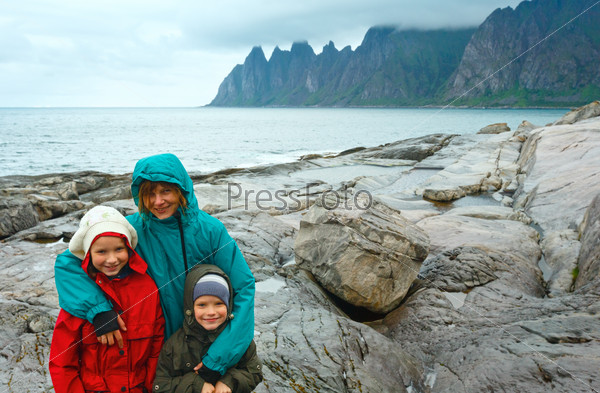 Family and summer night coast (polar day). The dragon\'s teeth rock, Jagged Ersfjord, Senja, Norway .