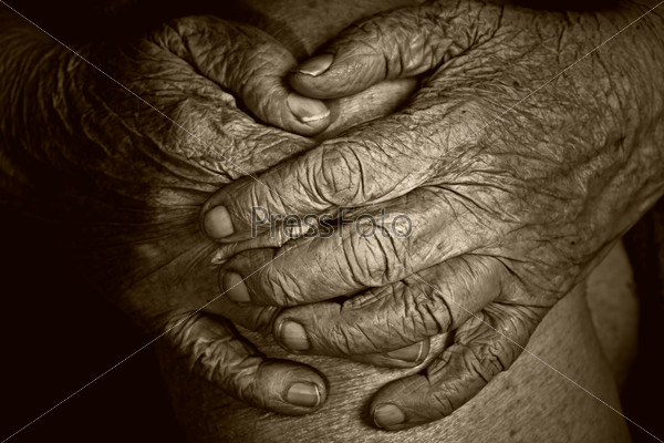 Hands of an old woman on her knees crossed