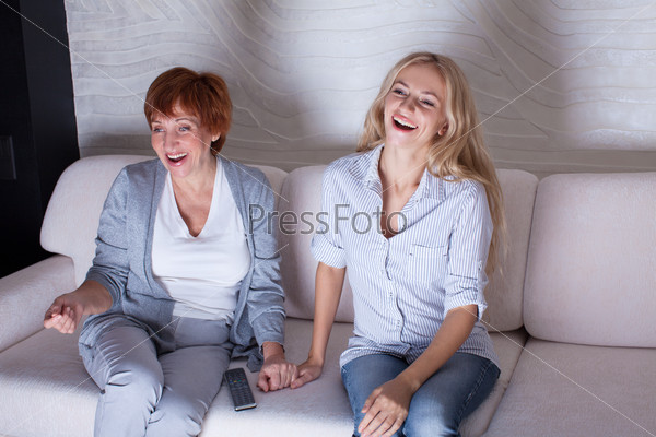 Mother with adult daughter watching television. Women looking film comedy