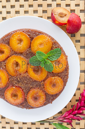 Overhead view of Upside down plum cake with tropical flower on side