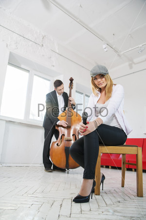 Woman on stool with microphone and man plays