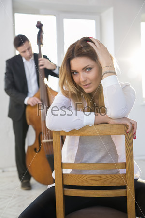 Young woman on chair and man with contrabass