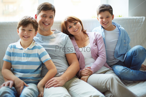 Portrait of happy family of four looking at camera with smiles