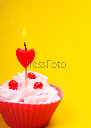 Tasty anniversary cupcake with candle, on yellow background