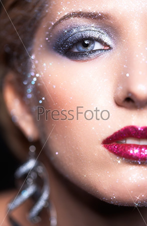 Low depth of focus portrait of beautiful young woman with vogue shining sparkle face makeup