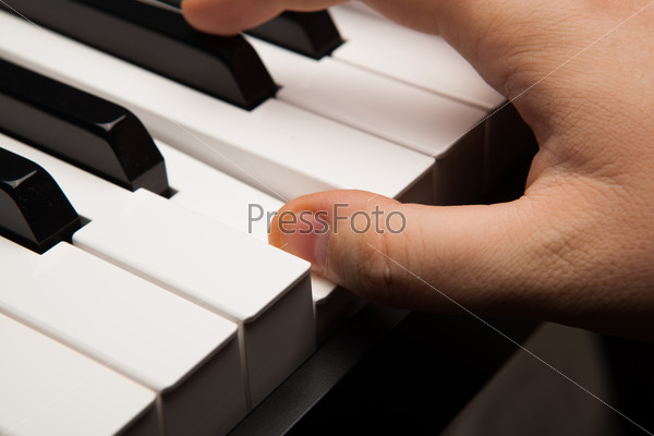 Piano keys and human finger close-up