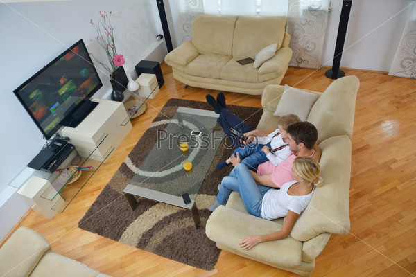 Happy young family with kids in bright modern living room have fun and looking big flat lcd tv, stock photo