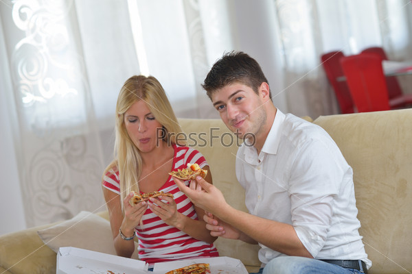 happy young couple eat fresh pizza at home relaxing and watch tv