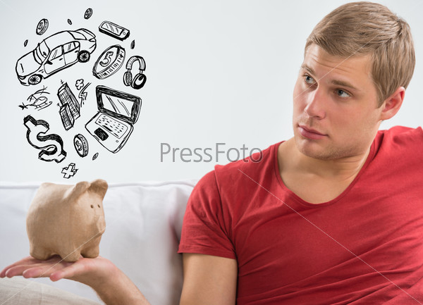 Handsome casual man with piggy bank in the living room at home. Savings concept
