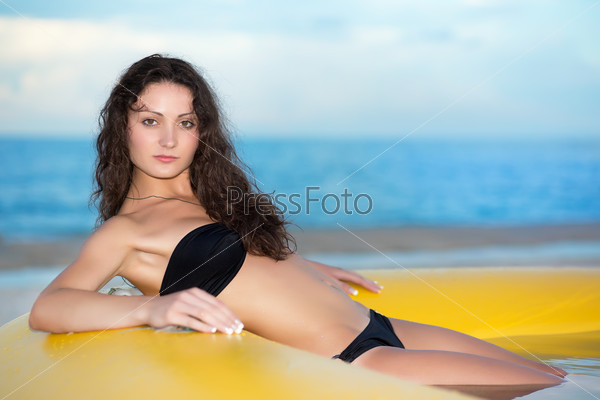 Young charming lady wearing black swimsuit posing in the yellow pool